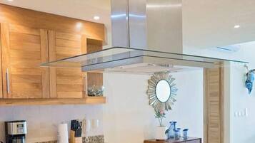 A modern kitchen with wooden cabinets, a granite countertop, and a stainless steel range hood.