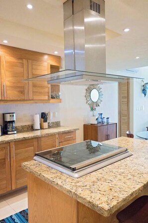 A modern kitchen with wooden cabinets, a granite countertop, and a stainless steel range hood.