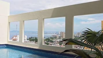 A swimming pool with a view of a cityscape through large windows.