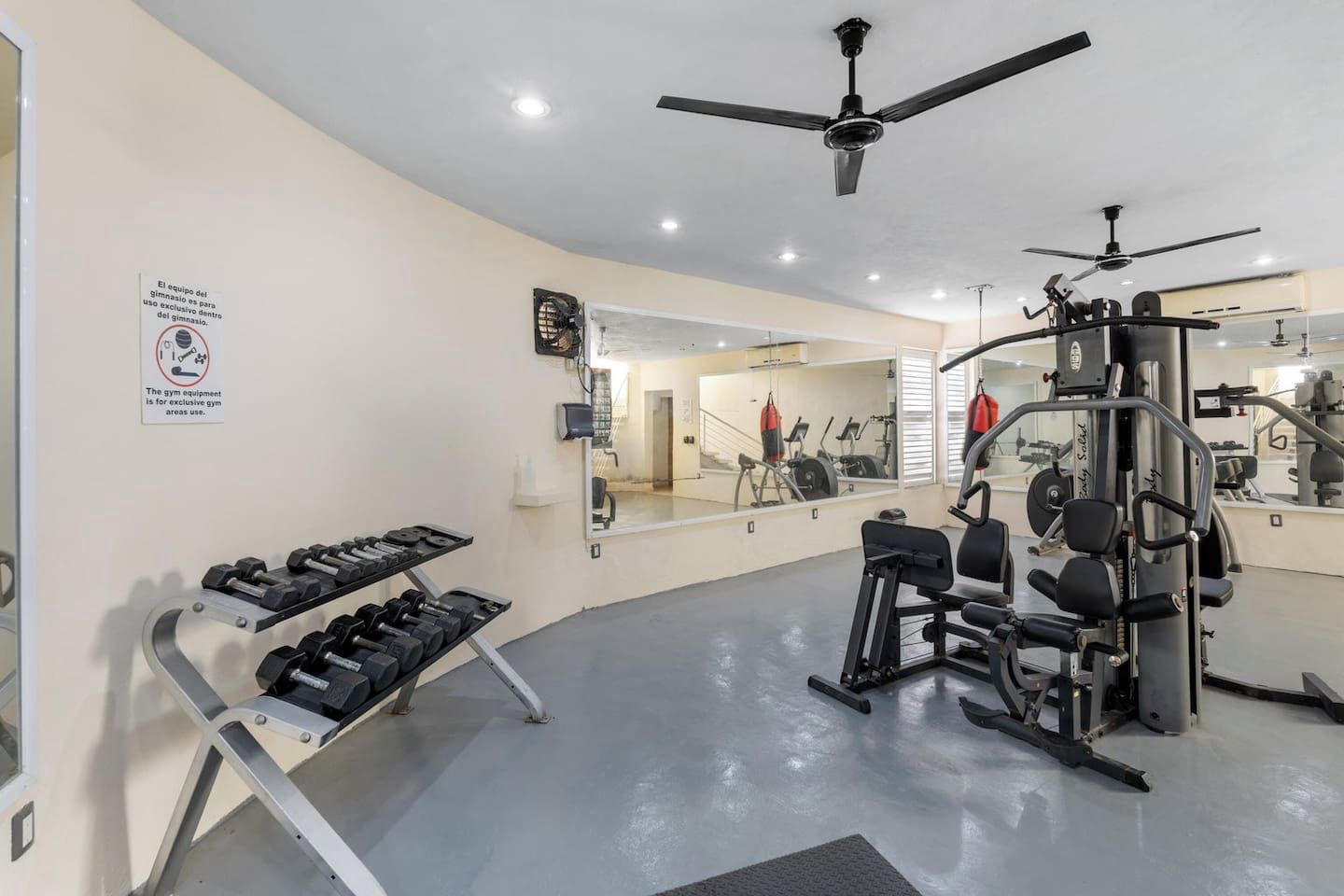 Une salle de sport équipée de matériel d’exercice, d’un ventilateur de plafond et d’un miroir.