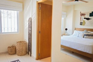 A bedroom with a bed, a bedside table, a lamp, and a window.