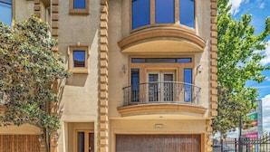 Ein zweistöckiges Haus mit einem gebogenen Balkon, einer Garage und Blick auf die Straße.
