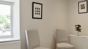 Una habitación con dos sillas, un radiador, una ventana y un cuadro en la pared.