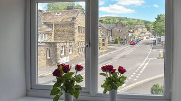 A window with a view of a street, a building labeled 'GEORGE HOTEL,' and two vases with flowers.