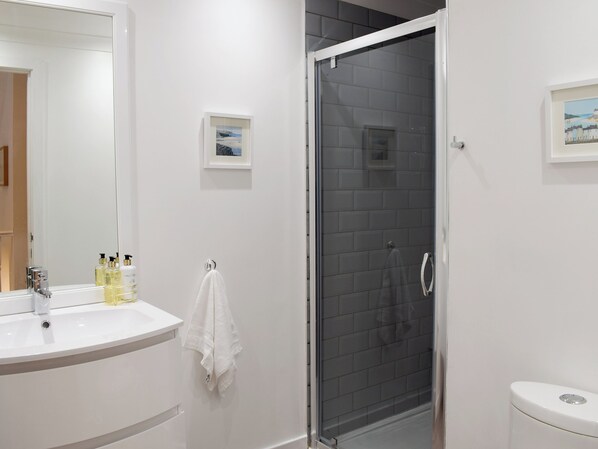 A modern bathroom with a white sink, a glass shower enclosure, and a toilet.