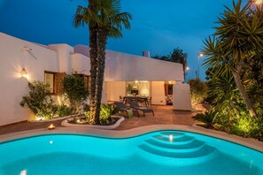 Una casa moderna con piscina, area salotto esterna e patio ben illuminato.