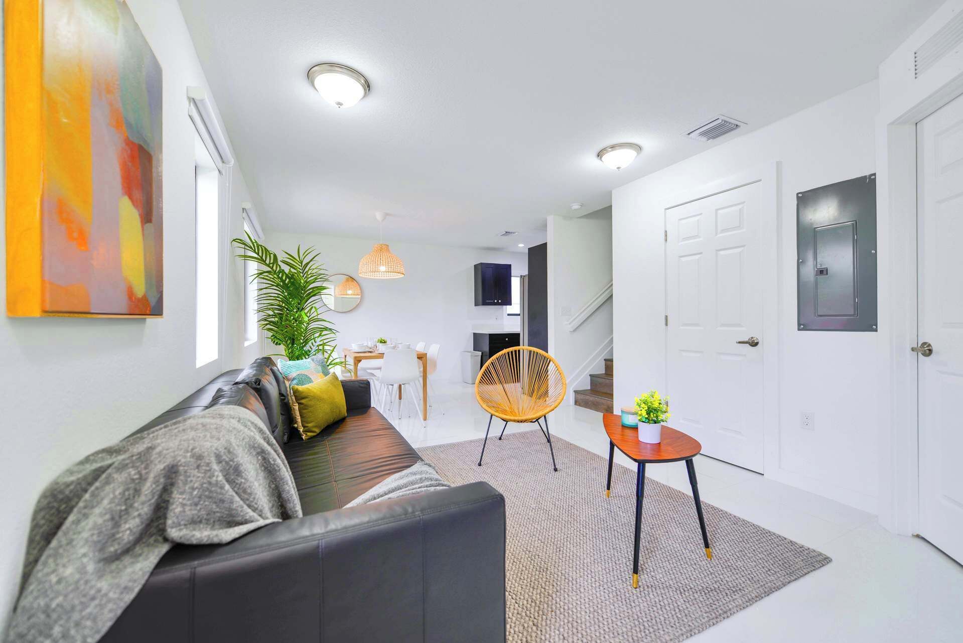 Een moderne woonkamer met een bank, een eethoek en een trap.