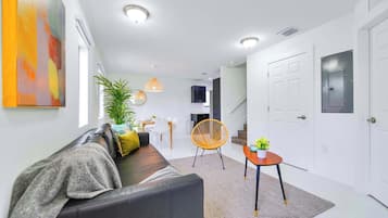 Een moderne woonkamer met een bank, een eethoek en een trap.