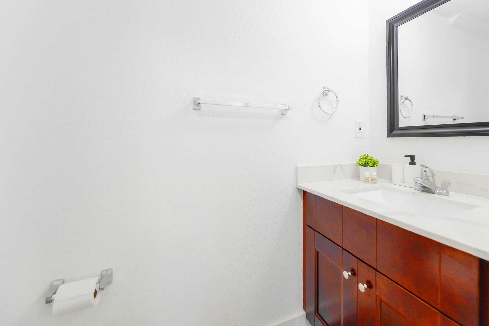 Une salle de bain avec un lavabo blanc, un miroir et des meubles en bois.