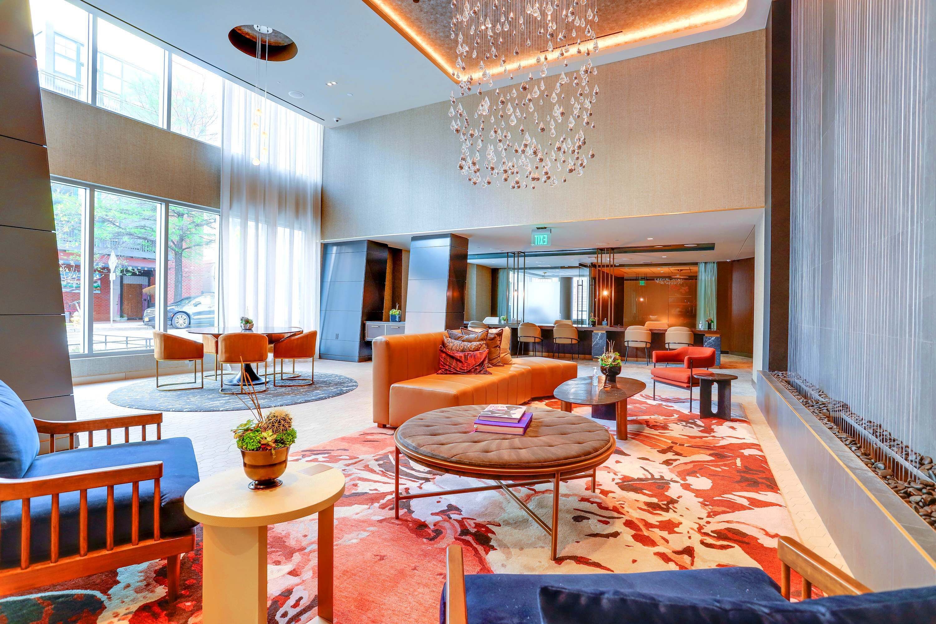 Un vestíbulo espacioso con diseño moderno, que incluye una amplia zona de estar con sofás y sillones, una mesa de centro redonda y una lámpara decorativa.