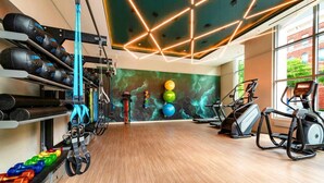 Une salle de sport équipée de matériel d’exercice, un mur décoré de balles colorées et un plancher en bois.