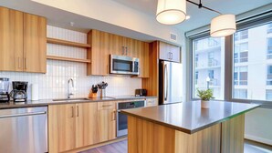 Une cuisine moderne avec des meubles en bois, des appareils en acier inoxydable et une grande fenêtre qui laisse entrer la lumière naturelle.