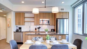 Une cuisine moderne avec des meubles en bois, des appareils en acier inoxydable et un coin repas aménagé pour quatre personnes.