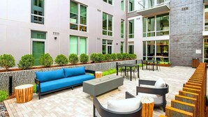 Un espace extérieur aménagé avec un canapé bleu, des fauteuils de jardin gris et une table en bois.