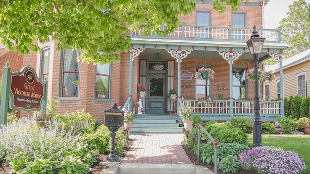 A brick building with a porch, steps leading to the entrance, and a sign indicating it's a lodging and events venue. - Boonville Luxury Lodging (Boonville)