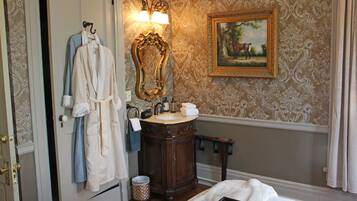 A bathroom with a wooden vanity, a mirror, a sink, and a painting on the wall.