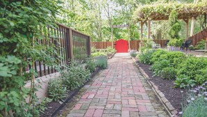 A brick pathway leading to a wooden pergola with a red gate. - Boonville Luxury Lodging (Boonville)