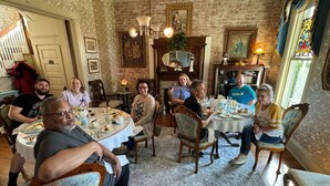 A dining room with round tables and chairs, a brick wall, and a large window with curtains. - Boonville Luxury Lodging (Boonville)
