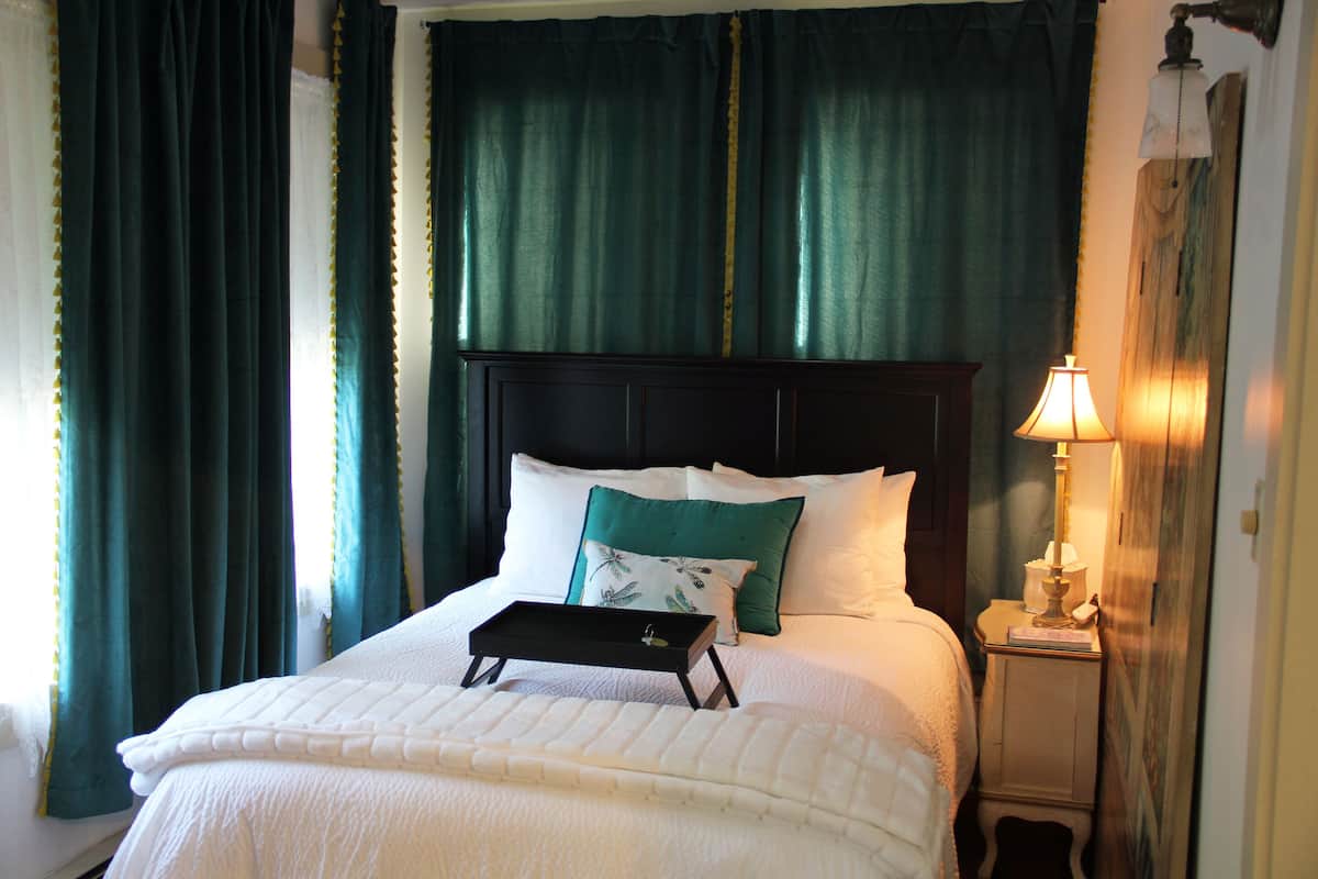 A neatly made bed with a tray, pillows, and a bedside lamp.