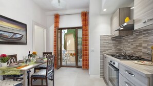 A modern kitchen with a gas stove, oven, and a dining area with a table set for two. - B&b-apartment-sleeps3-parking-balcony-petfriendly (Sorrento)