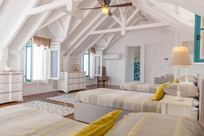 A spacious attic bedroom with high ceilings, a sloped roof, and a large bed with yellow pillows.