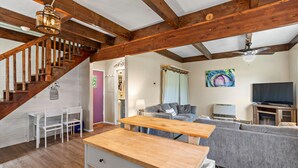 A spacious living area with a wooden staircase, a sofa, a TV, and a ceiling fan. - The GreenHouse - walk to the heart of Palmer, AK (Palmer)