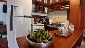 A kitchen with wooden cabinets, a refrigerator, an oven, and a sink. - Agradável Apartamento 2quartos Próximo ao Lago Negro a 4min do Centro (Gramado)