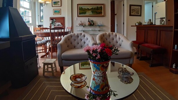 A cozy living room with a fireplace, a dining area, and a kitchen. - Agradável Apartamento 2quartos Próximo ao Lago Negro a 4min do Centro (Gramado)