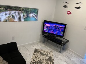 Relax in this stylish living room with a flat-screen TV, framed artwork, and a comfortable sofa.