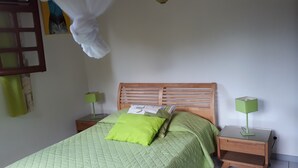 A bedroom with a bed, two bedside tables, and two green lamps. - Les Ixoras, quiet, flower-filled gîte in green setting 6 km from town and beaches. (La Trinité)