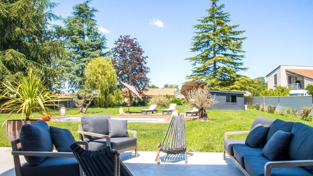 A backyard with outdoor seating, a pool, and a house in the background.