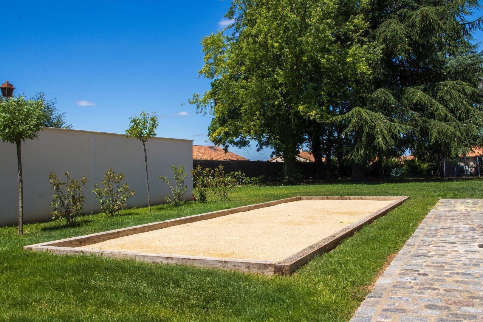 A courtyard with a sandbox, a paved path, and a white wall.