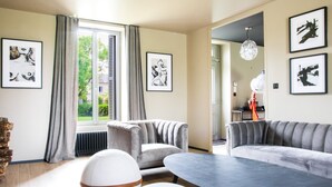 A modern living room with a sofa, armchairs, a coffee table, and artwork on the walls.