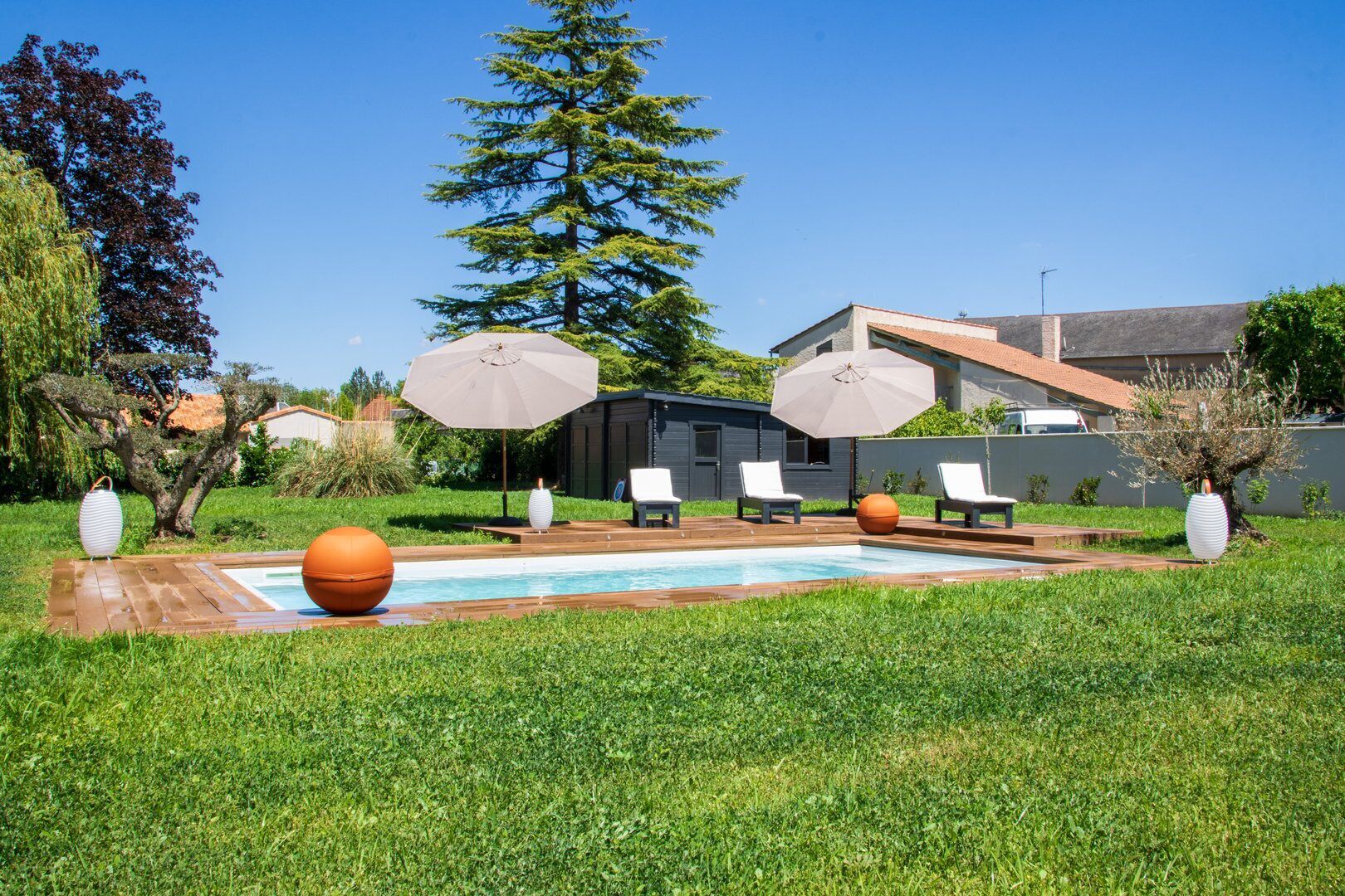 A backyard with a swimming pool, lounge chairs, and decorative elements.