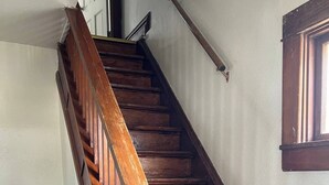 Eine Holztreppe mit Geländer und einem Fenster auf der rechten Seite.