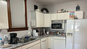 Eine Küche mit weißen Schränken, einer Mikrowelle, einem Kühlschrank, einer Kaffeemaschine und einem Toaster.