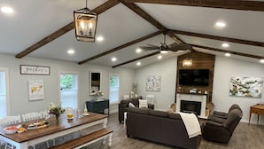 A spacious living room with a wooden ceiling, a fireplace, a dining area with a bench, and a sofa set. - The Silliman House - New renovation, Farmhouse Chic, close to baseball parks (maryland)