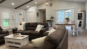 A spacious living room with brown leather sofas, a wooden coffee table, and a dining area with a wooden table and white chairs. - The Silliman House - New renovation, Farmhouse Chic, close to baseball parks (maryland)