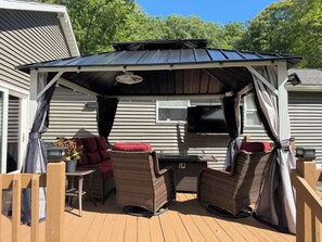 Un espace extérieur abrité, aménagé avec des meubles en osier et doté d’un barbecue.