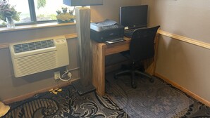A home office with a desk, computer, printer, and a large window with a view of greenery. - Baranof Lodge (Sitka)