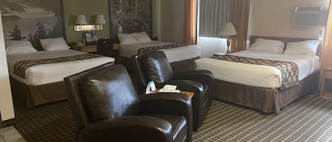 A hotel room with two beds, a sofa, and a desk.
