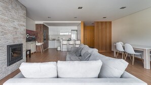 Een moderne woonkamer met een open haard, een bank en een eethoek met stoelen.