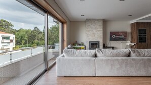 Een moderne woonkamer met een groot raam, een stenen open haard en een flatscreen televisie.