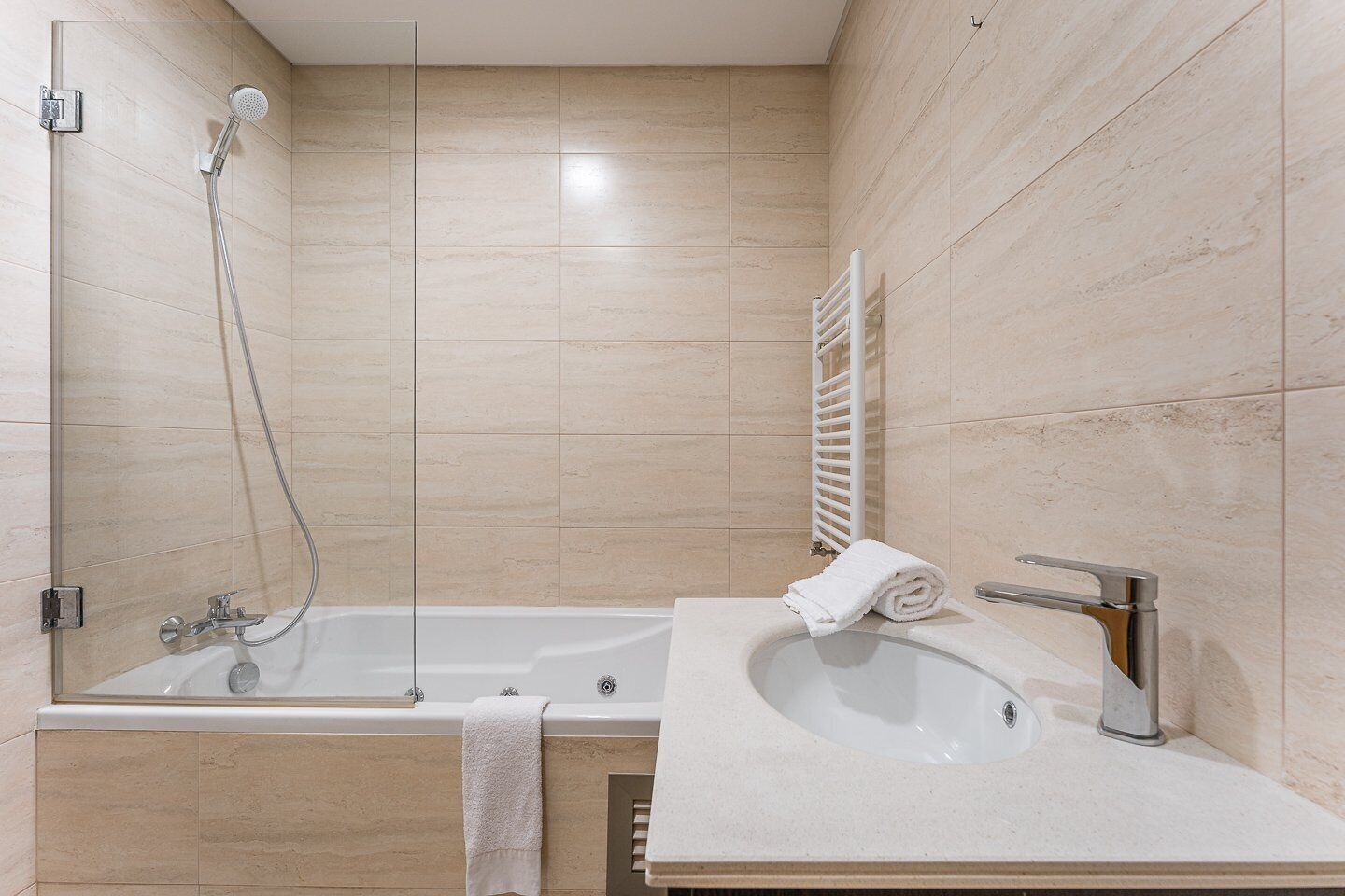 Ein modernes Badezimmer mit einer Duschkabine, einer freistehenden Badewanne und einem Waschbecken mit Handtuch auf der Ablagefläche.