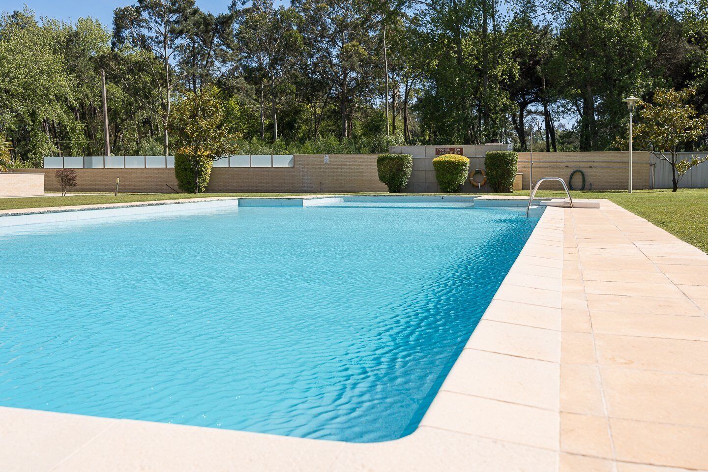 A rectangular swimming pool with a tiled deck surrounding it.