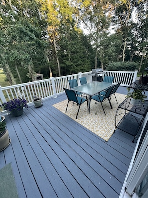 A deck with a table and chairs, surrounded by a white railing and potted plants.