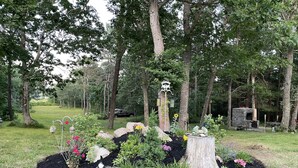 A garden with a stone fireplace, a bird feeder, and a wooden sign.