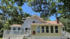 A two-story house with a porch, a chimney, and a small statue on the front lawn.