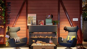 Un área de descanso moderna con dos sillones de respaldo alto, una mesa de centro y una chimenea.