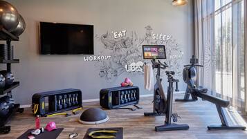 A modern gym with a large TV, exercise equipment, and motivational wall art.